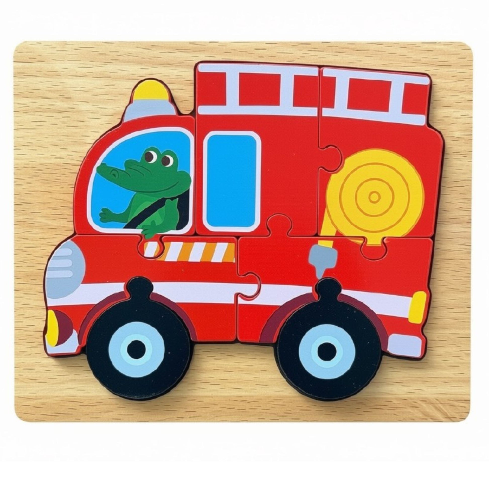 A wooden fire truck jigsaw puzzle set on a light wood background. The puzzle features a red fire truck with white stripes, black wheels with light blue centers, a yellow hose, a yellow light, and a green cartoon frog driver in the window.